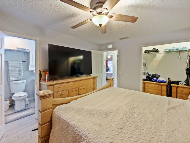 bedroom with ensuite bath, ceiling fan, a textured ceiling, and light wood-type flooring