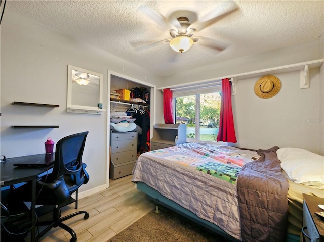 bedroom with ceiling fan, light wood-type flooring, a textured ceiling, and a closet