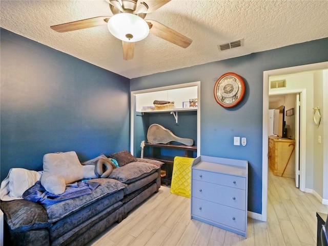 interior space featuring ceiling fan, light hardwood / wood-style floors, a textured ceiling, and a closet