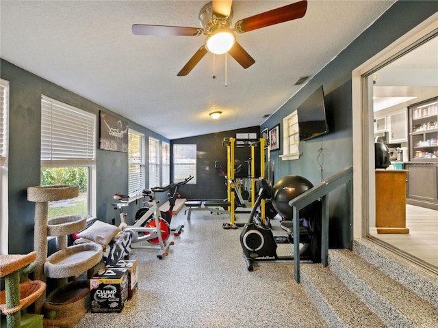 exercise room featuring a textured ceiling, ceiling fan, and lofted ceiling