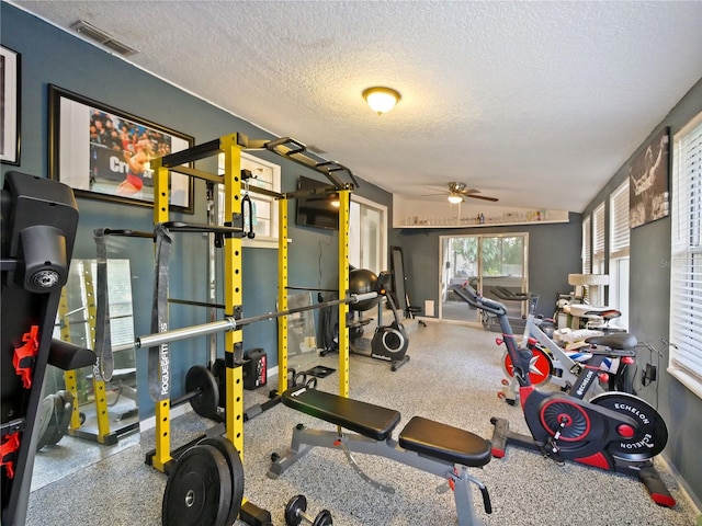 exercise area with ceiling fan, lofted ceiling, and a textured ceiling