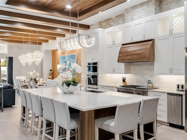 kitchen with white cabinetry, a kitchen island with sink, pendant lighting, and custom exhaust hood