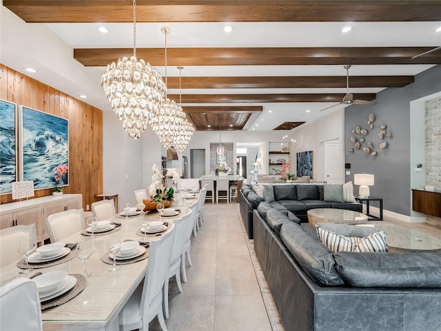 dining space with beam ceiling, wood walls, and ceiling fan with notable chandelier