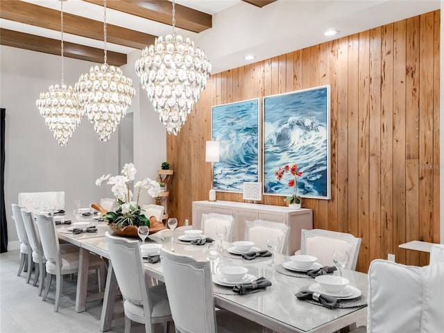 dining space featuring wood walls, a notable chandelier, and beam ceiling