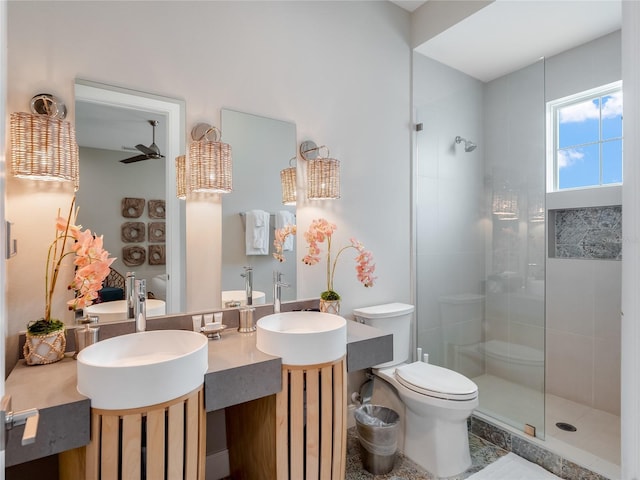 bathroom featuring toilet, ceiling fan, a tile shower, and vanity