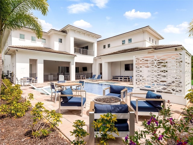 back of house featuring a pool with hot tub, a patio area, an outdoor hangout area, and a balcony