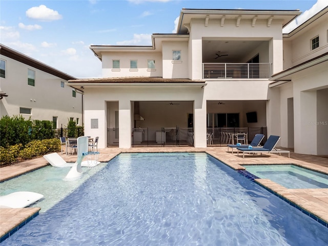 back of house with a swimming pool with hot tub and a patio area