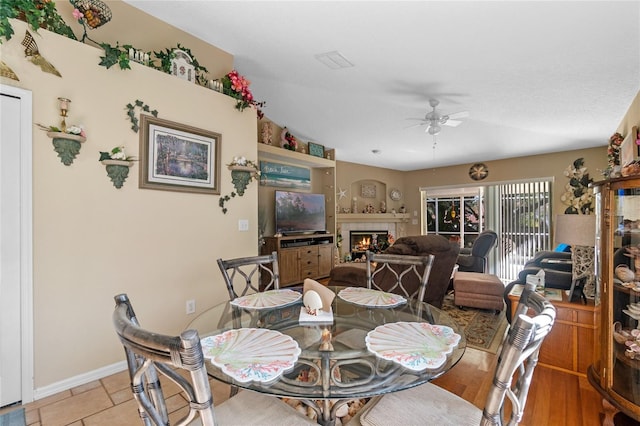 tiled dining area with a tile fireplace and ceiling fan