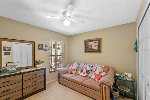 living room featuring a textured ceiling, ceiling fan, and light carpet