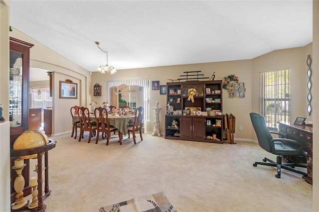 dining room featuring light carpet, a textured ceiling, an inviting chandelier, and lofted ceiling