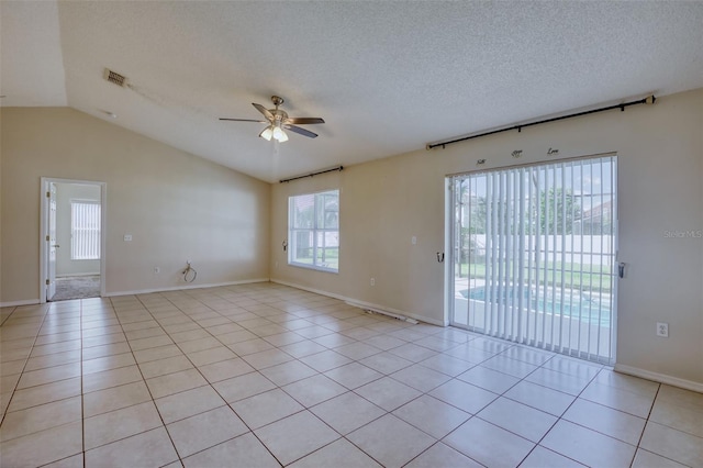 empty room with a textured ceiling, vaulted ceiling, ceiling fan, and light tile patterned flooring