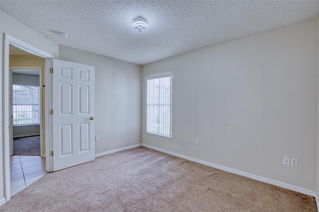 carpeted empty room featuring a textured ceiling and a wealth of natural light