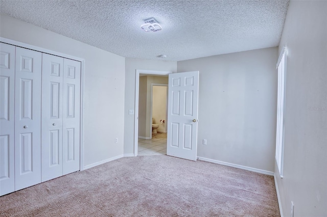 unfurnished bedroom featuring a textured ceiling, light colored carpet, and a closet