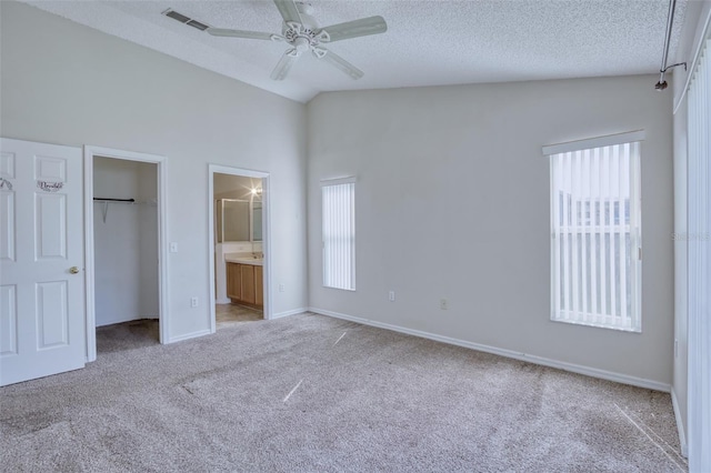 unfurnished bedroom featuring multiple windows, ensuite bathroom, ceiling fan, and vaulted ceiling