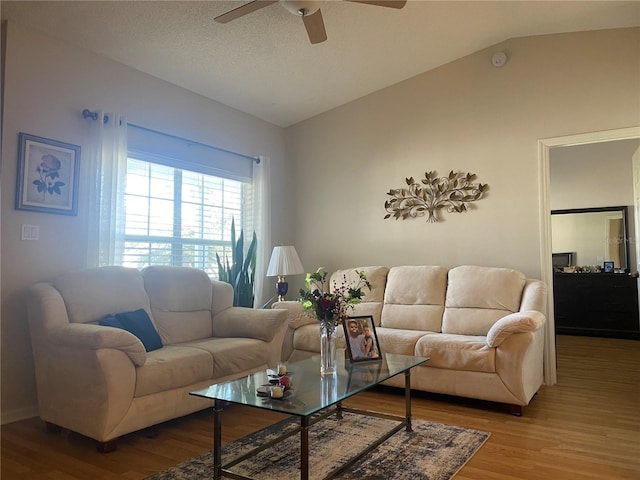 living room with a textured ceiling, hardwood / wood-style flooring, vaulted ceiling, and ceiling fan