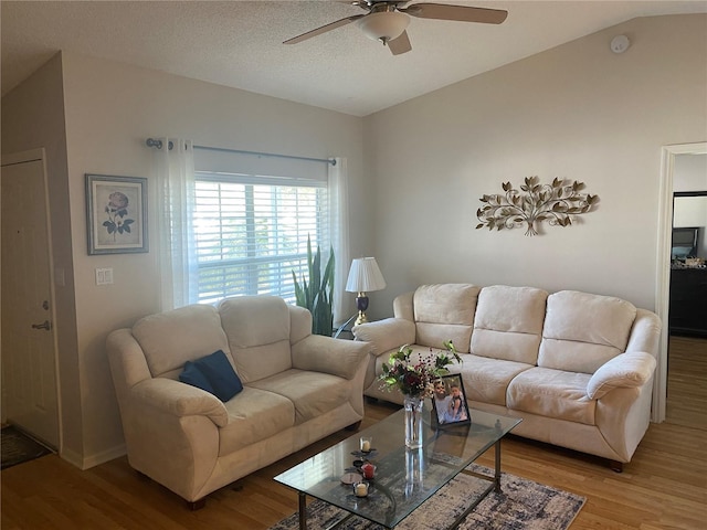 living room with a textured ceiling, light wood-type flooring, ceiling fan, and lofted ceiling