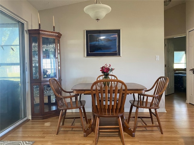 dining area featuring a healthy amount of sunlight, light hardwood / wood-style floors, and vaulted ceiling