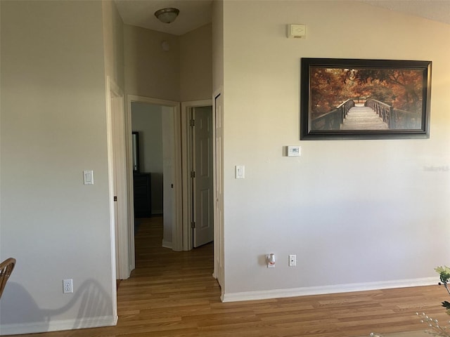 corridor with hardwood / wood-style floors and lofted ceiling