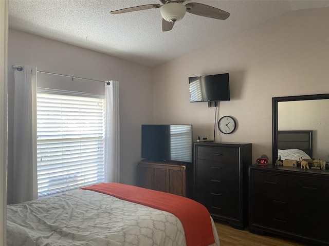 bedroom featuring a textured ceiling, ceiling fan, vaulted ceiling, and hardwood / wood-style flooring