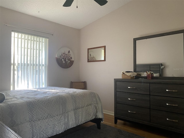 bedroom featuring ceiling fan, dark hardwood / wood-style flooring, lofted ceiling, and a textured ceiling