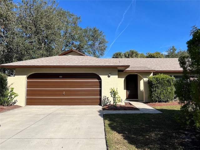 ranch-style home featuring a garage, concrete driveway, roof with shingles, and stucco siding