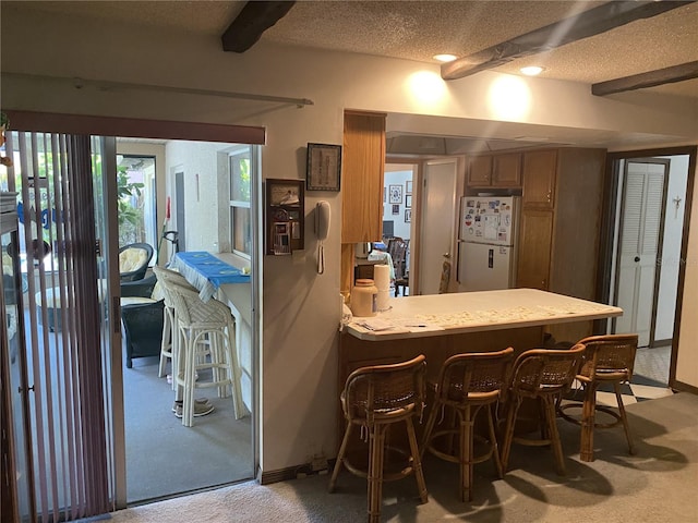 kitchen featuring a kitchen breakfast bar, kitchen peninsula, white fridge, light colored carpet, and a textured ceiling