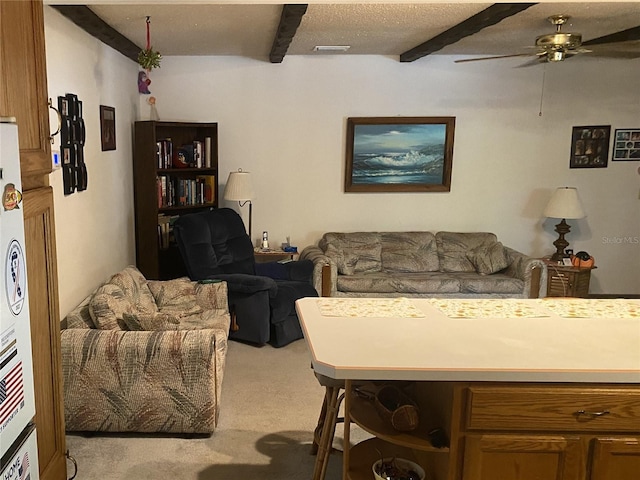 living room with ceiling fan, beam ceiling, light colored carpet, and a textured ceiling