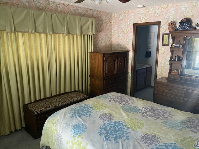 carpeted bedroom featuring ceiling fan, a textured ceiling, and ensuite bath