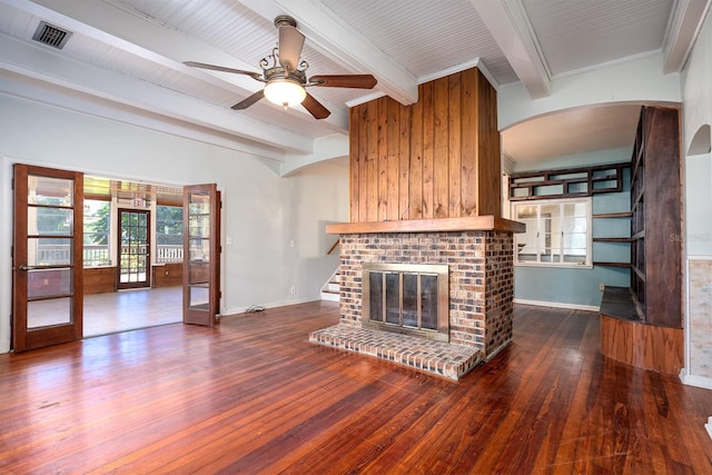 unfurnished living room featuring french doors, a fireplace, ceiling fan, hardwood / wood-style flooring, and beamed ceiling