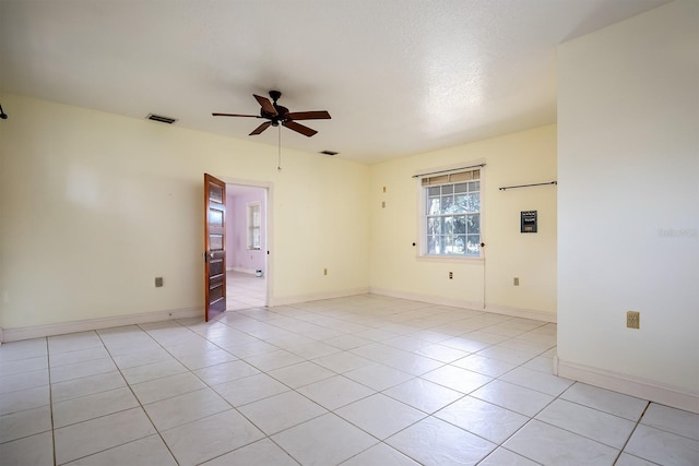 empty room with a textured ceiling, ceiling fan, and light tile patterned flooring