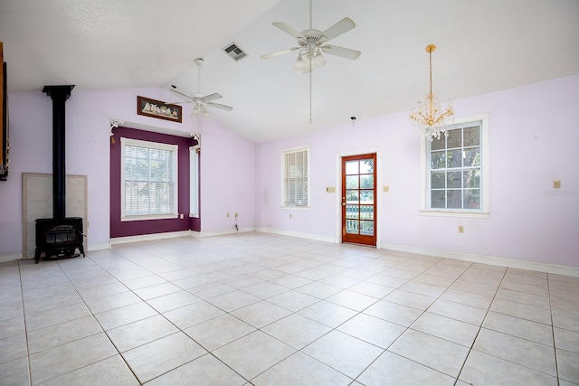 unfurnished living room featuring a wood stove, light tile patterned floors, ceiling fan with notable chandelier, and vaulted ceiling