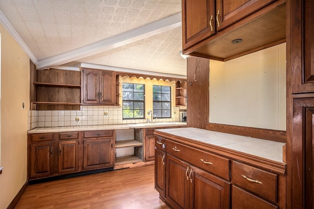 kitchen with sink, tile countertops, light hardwood / wood-style floors, decorative backsplash, and ornamental molding