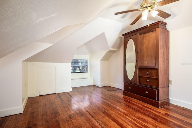 additional living space with a textured ceiling, lofted ceiling, ceiling fan, and dark hardwood / wood-style floors