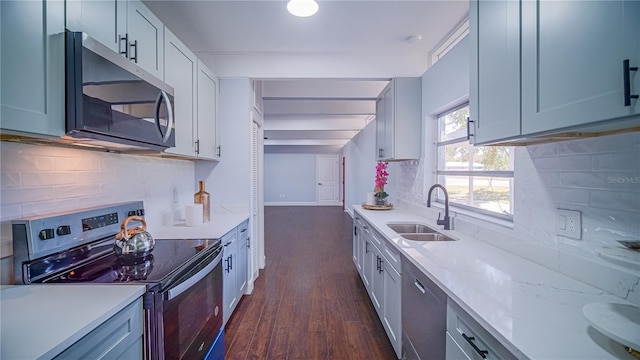 kitchen featuring appliances with stainless steel finishes, tasteful backsplash, light stone counters, dark wood-type flooring, and sink