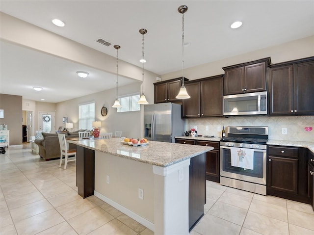 kitchen with light stone countertops, stainless steel appliances, decorative light fixtures, decorative backsplash, and dark brown cabinets