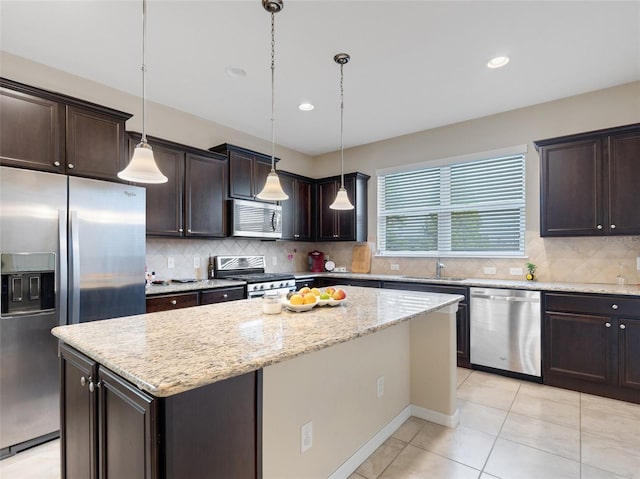 kitchen with dark brown cabinetry, sink, stainless steel appliances, decorative light fixtures, and a kitchen island