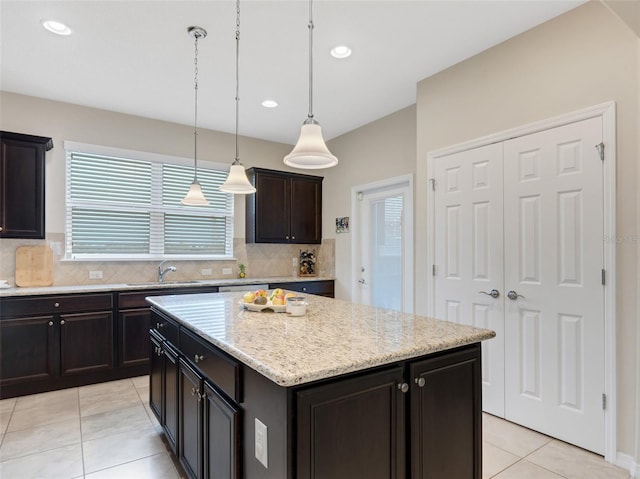 kitchen featuring a center island, backsplash, sink, decorative light fixtures, and dark brown cabinetry