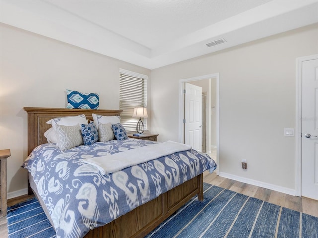 bedroom with a tray ceiling and hardwood / wood-style flooring