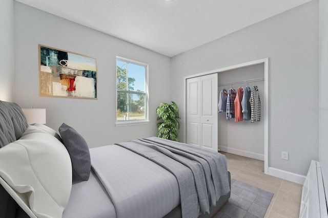 bedroom featuring a textured ceiling, a closet, tile patterned flooring, and baseboards