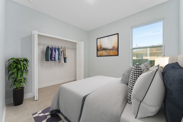 bedroom featuring a closet, light tile patterned flooring, and baseboards