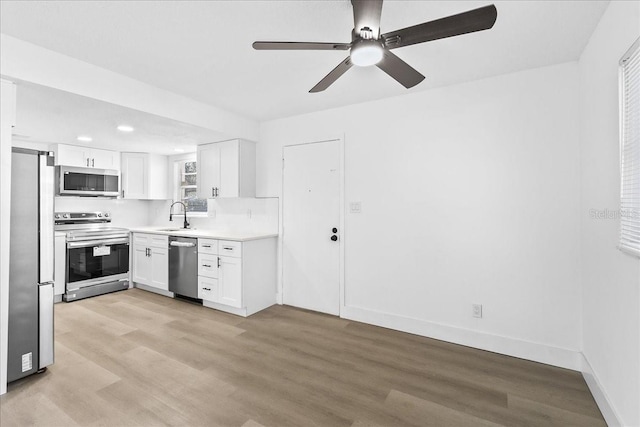 kitchen with appliances with stainless steel finishes, ceiling fan, sink, light hardwood / wood-style flooring, and white cabinetry