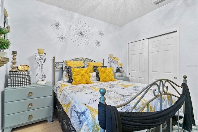 bedroom featuring a closet, a textured ceiling, and light hardwood / wood-style flooring