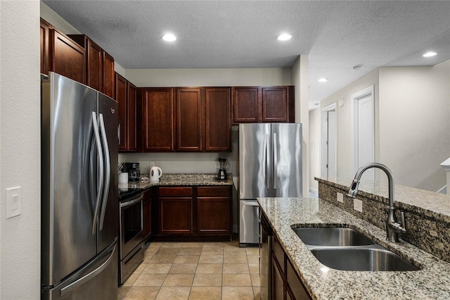 7639 Wilmington Loop, Kissimmee, FL 34747 - kitchen with appliances with stainless steel finishes, light stone counters, recessed lighting, a textured ceiling, and reddish brown cabinets