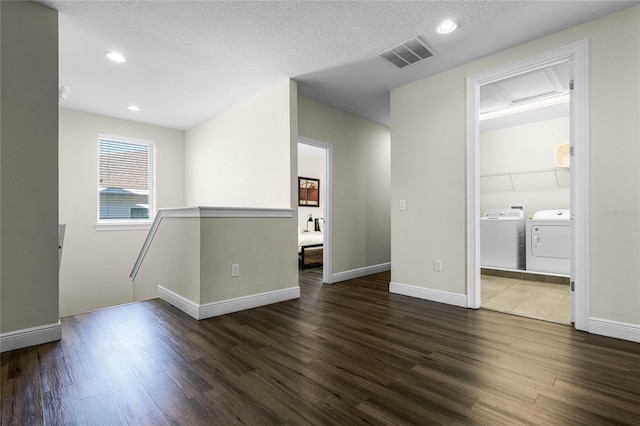 empty room featuring a textured ceiling, dark hardwood / wood-style flooring, and washing machine and clothes dryer