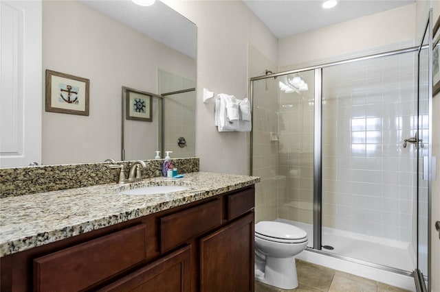 bathroom featuring tile patterned flooring, vanity, a shower with shower door, and toilet