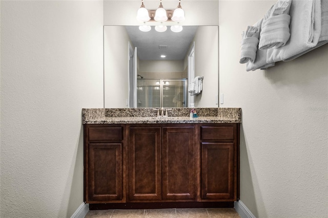 bathroom with tile patterned floors, vanity, an enclosed shower, and an inviting chandelier