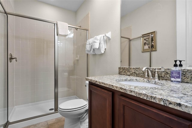 bathroom with tile patterned floors, vanity, an enclosed shower, and toilet