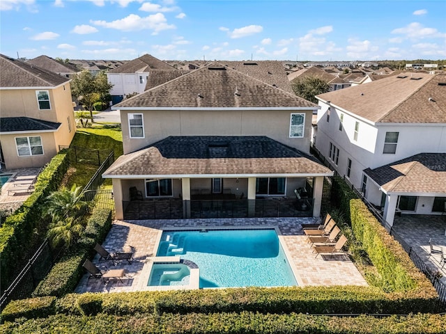 rear view of property with a patio and a pool with hot tub