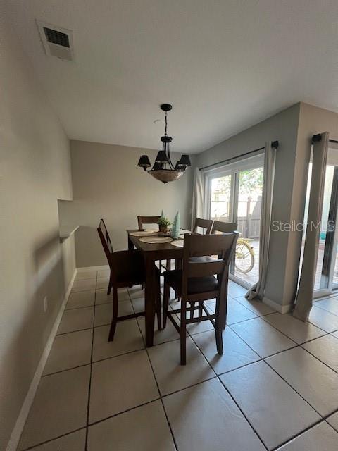 tiled dining space with an inviting chandelier