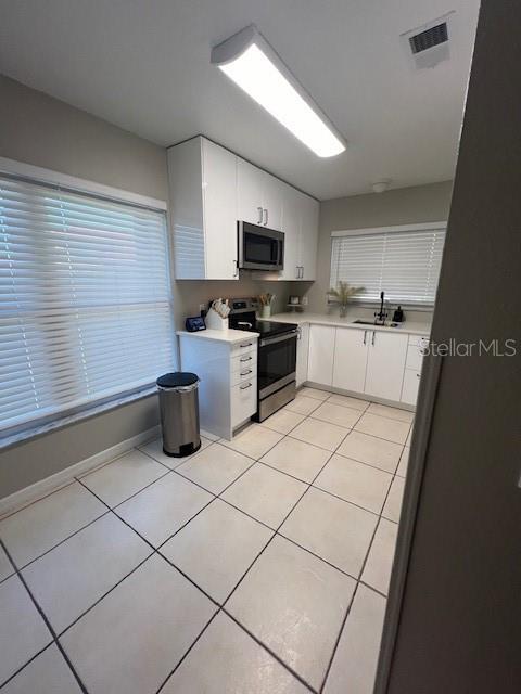 kitchen featuring white cabinetry, sink, light tile patterned floors, and stainless steel appliances